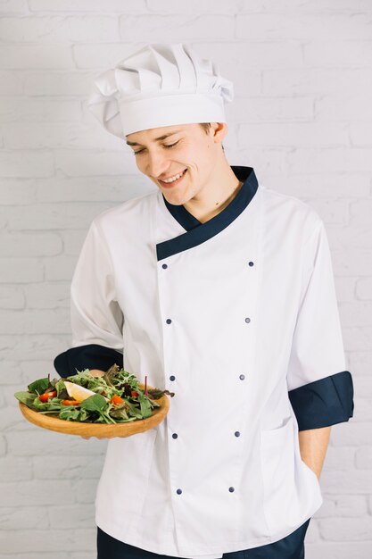 Cocinero con plato de madera y ensalada.