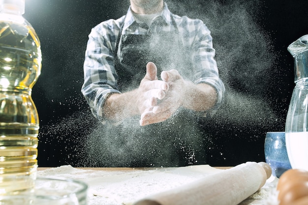 Foto gratuita cocinero profesional masculino espolvorea la masa con harina