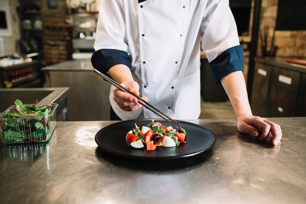 Foto gratuita cocinero de putting green en plato con ensalada.