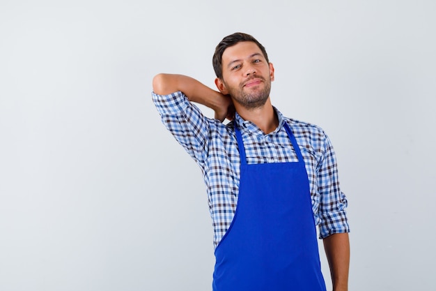 Foto gratuita cocinero de sexo masculino joven en un delantal azul y una camisa
