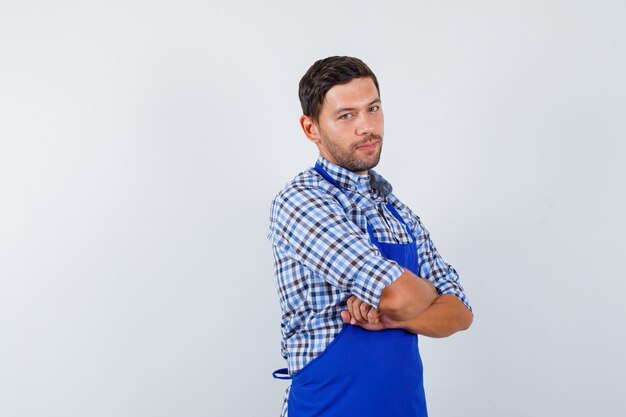 Cocinero de sexo masculino joven en un delantal azul y una camisa