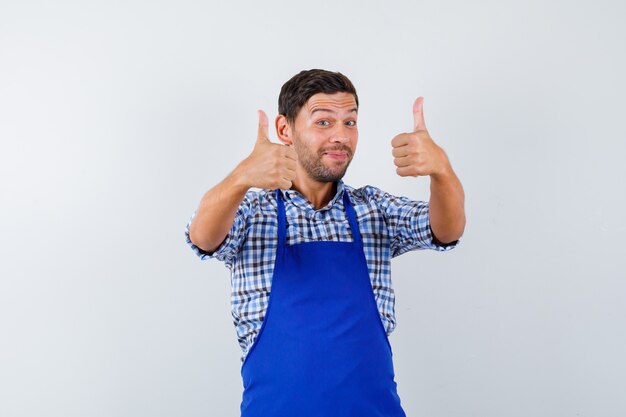 Cocinero de sexo masculino joven en un delantal azul y una camisa