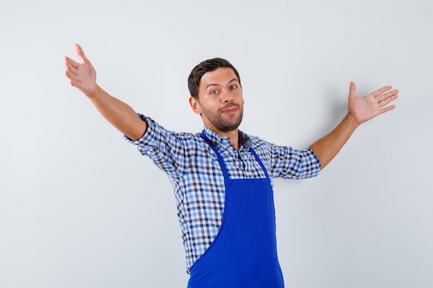 Cocinero de sexo masculino joven en un delantal azul y una camisa