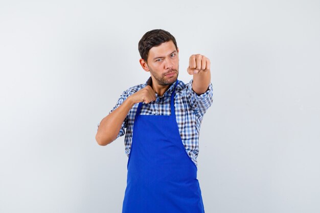 Cocinero de sexo masculino joven en un delantal azul y una camisa