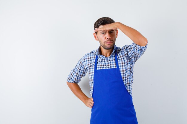 Cocinero de sexo masculino joven en un delantal azul y una camisa