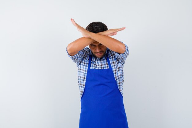 Cocinero de sexo masculino joven en un delantal azul y una camisa