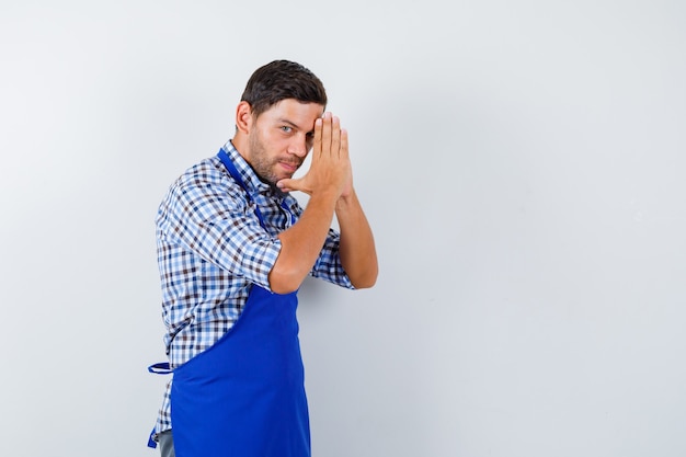 Foto gratuita cocinero de sexo masculino joven en un delantal azul y una camisa