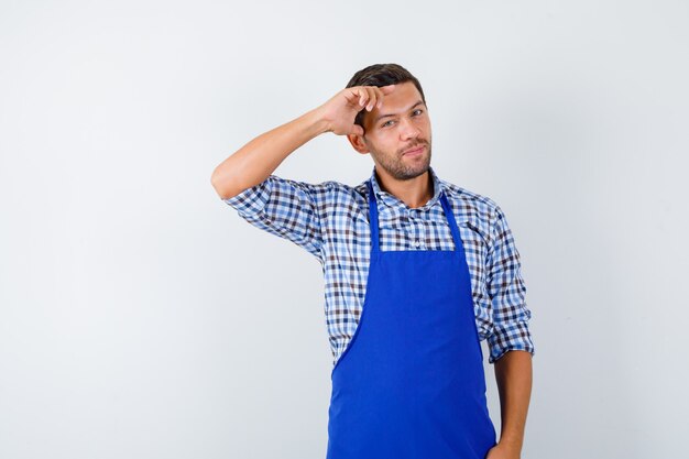 Cocinero de sexo masculino joven en un delantal azul y una camisa