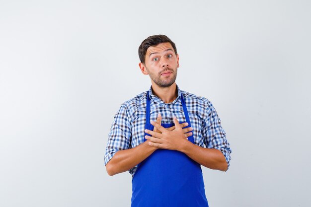 Cocinero de sexo masculino joven en un delantal azul y una camisa