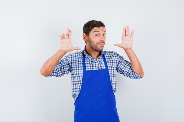 Cocinero de sexo masculino joven en un delantal azul y una camisa