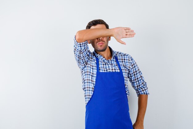 Cocinero de sexo masculino joven en un delantal azul y una camisa