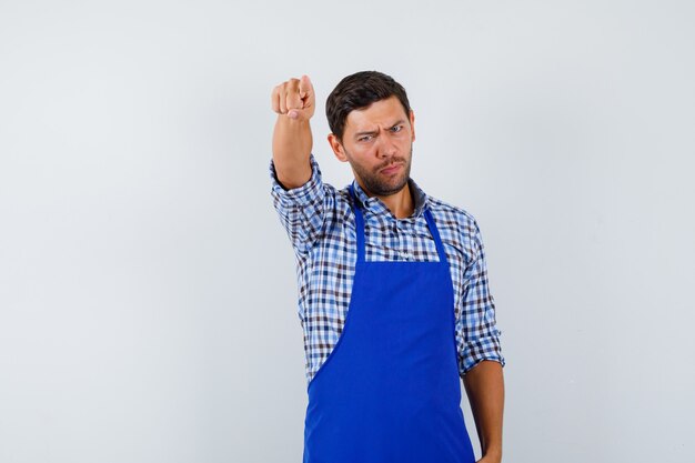 Cocinero de sexo masculino joven en un delantal azul y una camisa