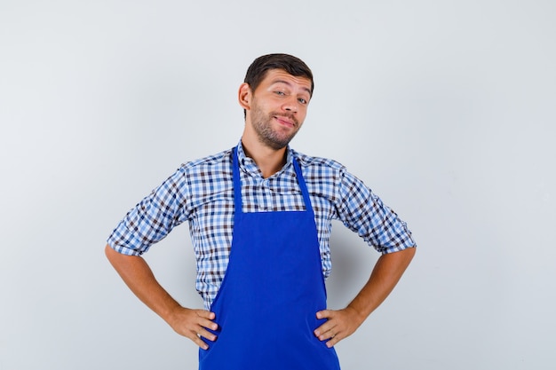 Cocinero de sexo masculino joven en un delantal azul y una camisa