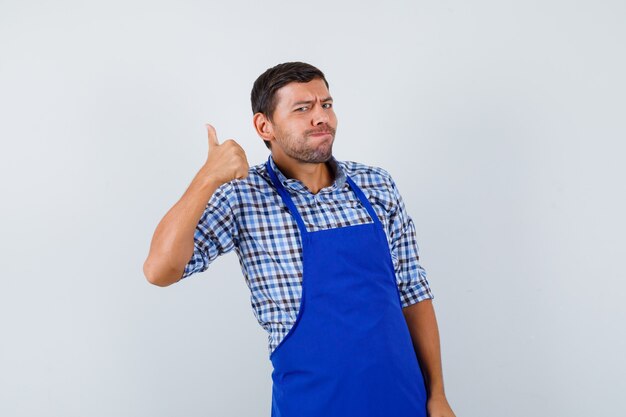 Cocinero de sexo masculino joven en un delantal azul y una camisa