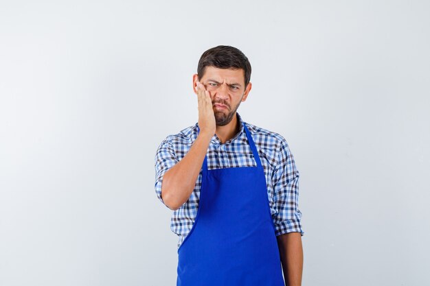 Cocinero de sexo masculino joven en un delantal azul y una camisa