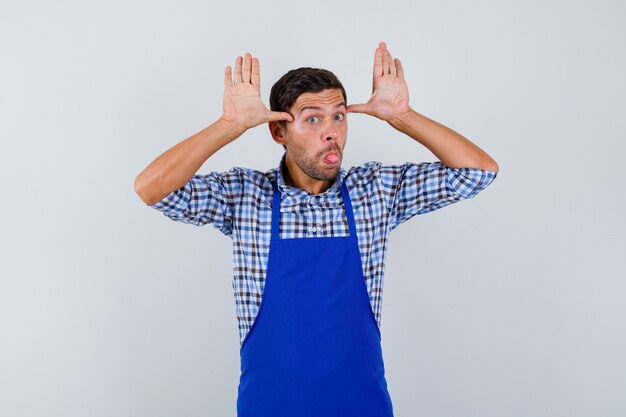 Cocinero de sexo masculino joven en un delantal azul y una camisa