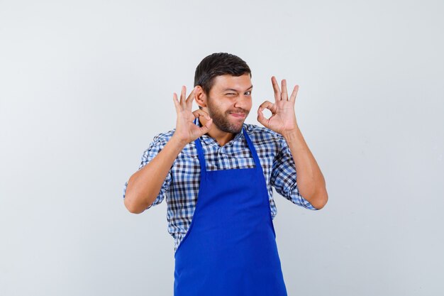 Cocinero de sexo masculino joven en un delantal azul y una camisa