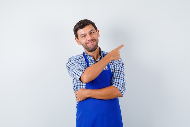 Foto gratuita cocinero de sexo masculino joven en un delantal azul y una camisa