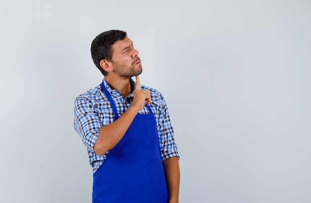 Foto gratuita cocinero de sexo masculino joven en un delantal azul y una camisa