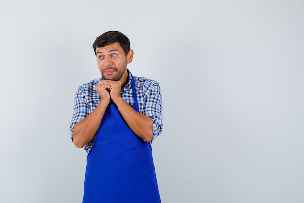 Foto gratuita cocinero de sexo masculino joven en un delantal azul y una camisa