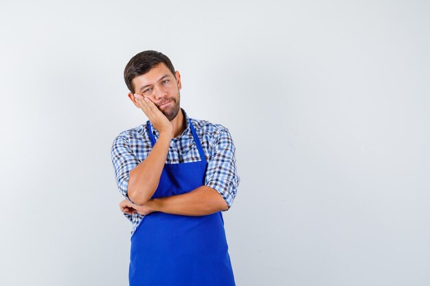 Cocinero de sexo masculino joven en un delantal azul y una camisa