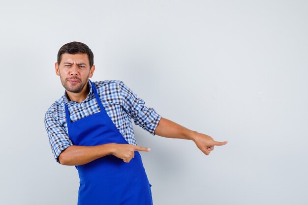 Cocinero de sexo masculino joven en un delantal azul y una camisa