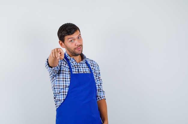 Cocinero de sexo masculino joven en un delantal azul y una camisa