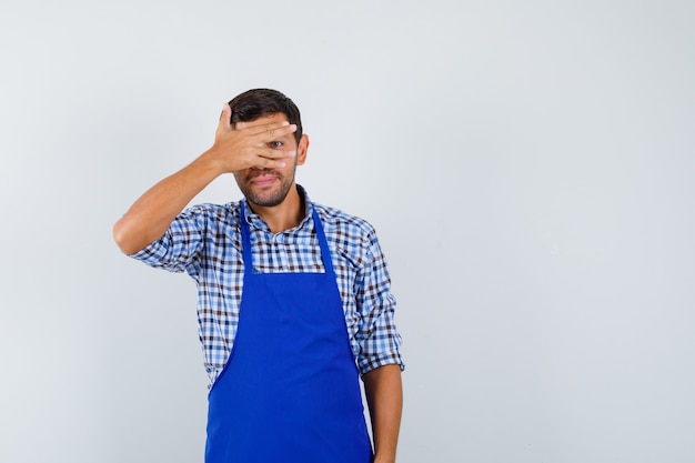 Cocinero de sexo masculino joven en un delantal azul y una camisa