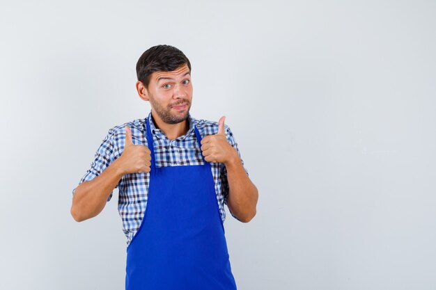 Cocinero de sexo masculino joven en un delantal azul y una camisa