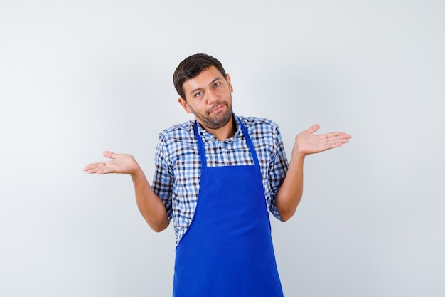 Cocinero de sexo masculino joven en un delantal azul y una camisa