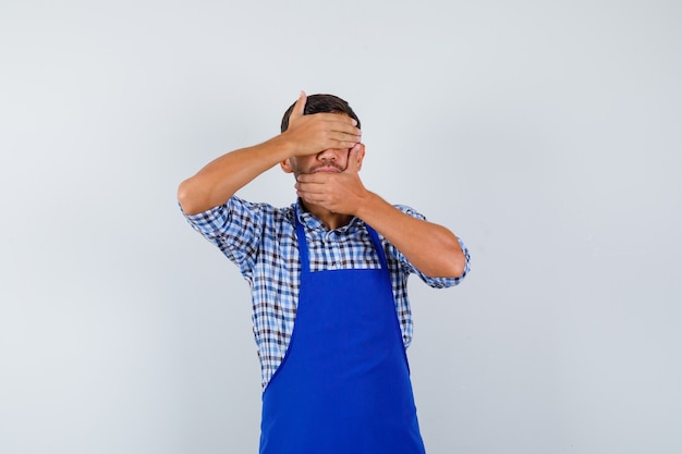 Cocinero de sexo masculino joven en un delantal azul y una camisa