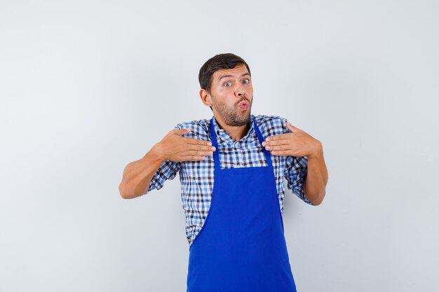 Cocinero de sexo masculino joven en un delantal azul y una camisa