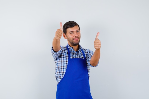 Cocinero de sexo masculino joven en un delantal azul y una camisa