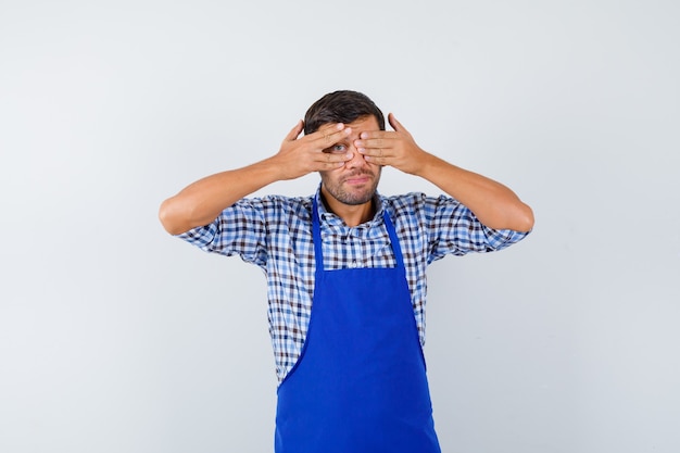 Cocinero de sexo masculino joven en un delantal azul y una camisa