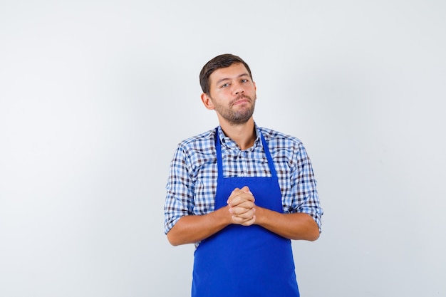 Cocinero de sexo masculino joven en un delantal azul y una camisa