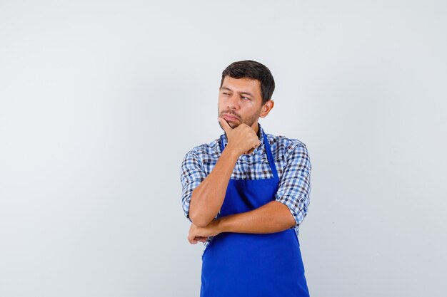 Cocinero de sexo masculino joven en un delantal azul y una camisa