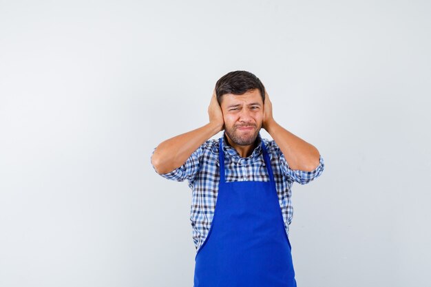 Cocinero de sexo masculino joven en un delantal azul y una camisa