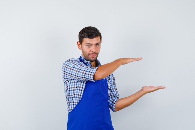 Cocinero de sexo masculino joven en un delantal azul y una camisa