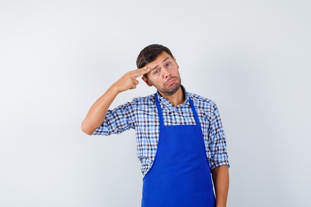 Cocinero de sexo masculino joven en un delantal azul y una camisa