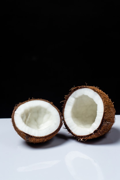 Foto gratuita coco cortado por la mitad en una mesa sobre un negro