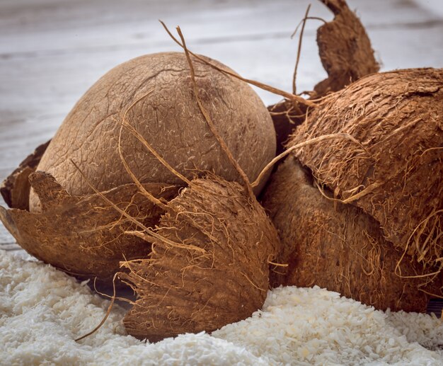 Coco nueces enteras esparcidas virutas de mesa de madera