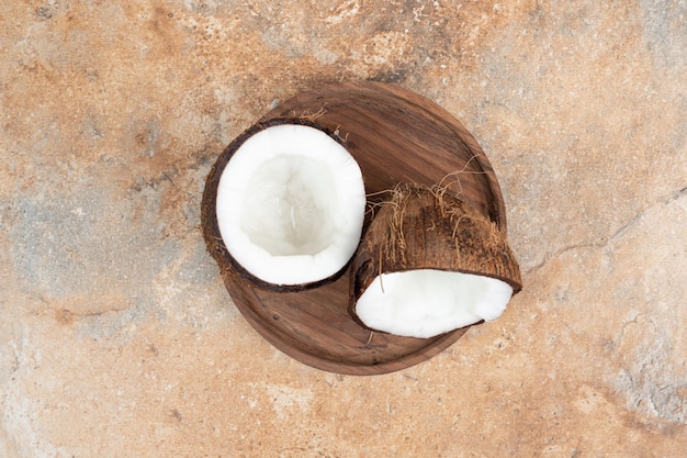 Foto gratuita cocos maduros medio cortados en placa de madera.