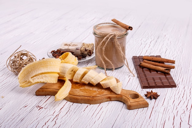 Coctail de desintoxicación con palitos de canela, plátanos y chocolate se encuentran sobre la mesa