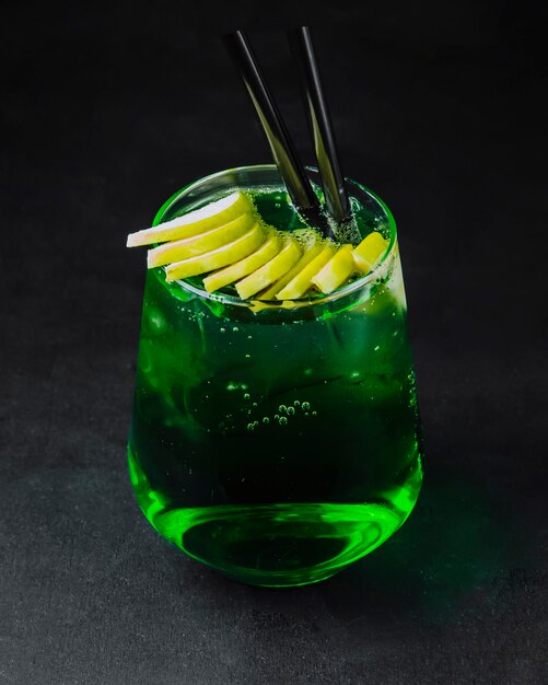 Cóctel de alcohol verde con rodajas de limón en la vista lateral superior