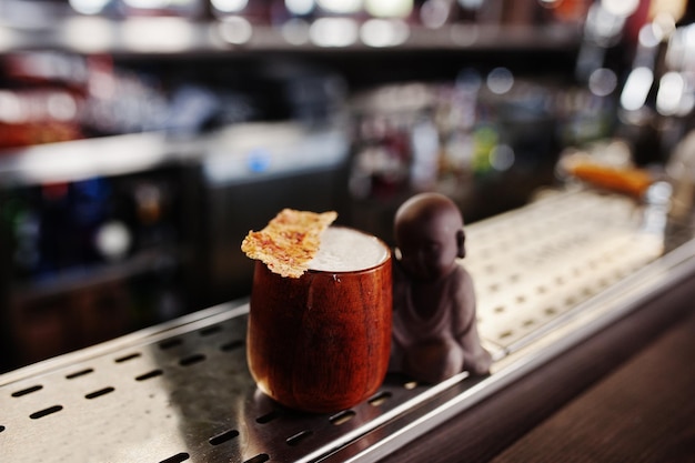 Cóctel alcohólico en taza de madera en la mesa del bar