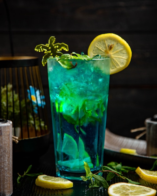 Cóctel azul con menta y limón en un vaso.