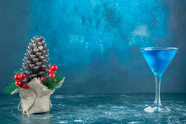 Foto gratuita cóctel azul en un vaso junto al adorno navideño en mármol.