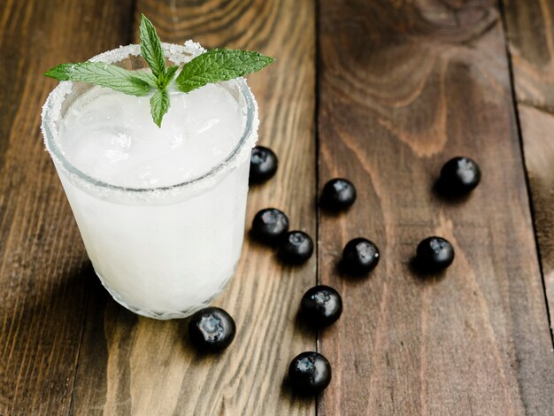 Cóctel blanco con hielo junto a arándanos.