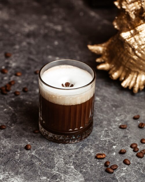 Un cóctel de café de vista frontal con hielo y semillas de café en el escritorio gris cóctel de jugo de bebida