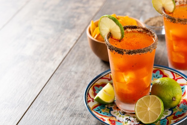 Foto gratuita cóctel casero de michelada con cerveza, jugo de lima, salsa picante, borde salado y jugo de tomate.